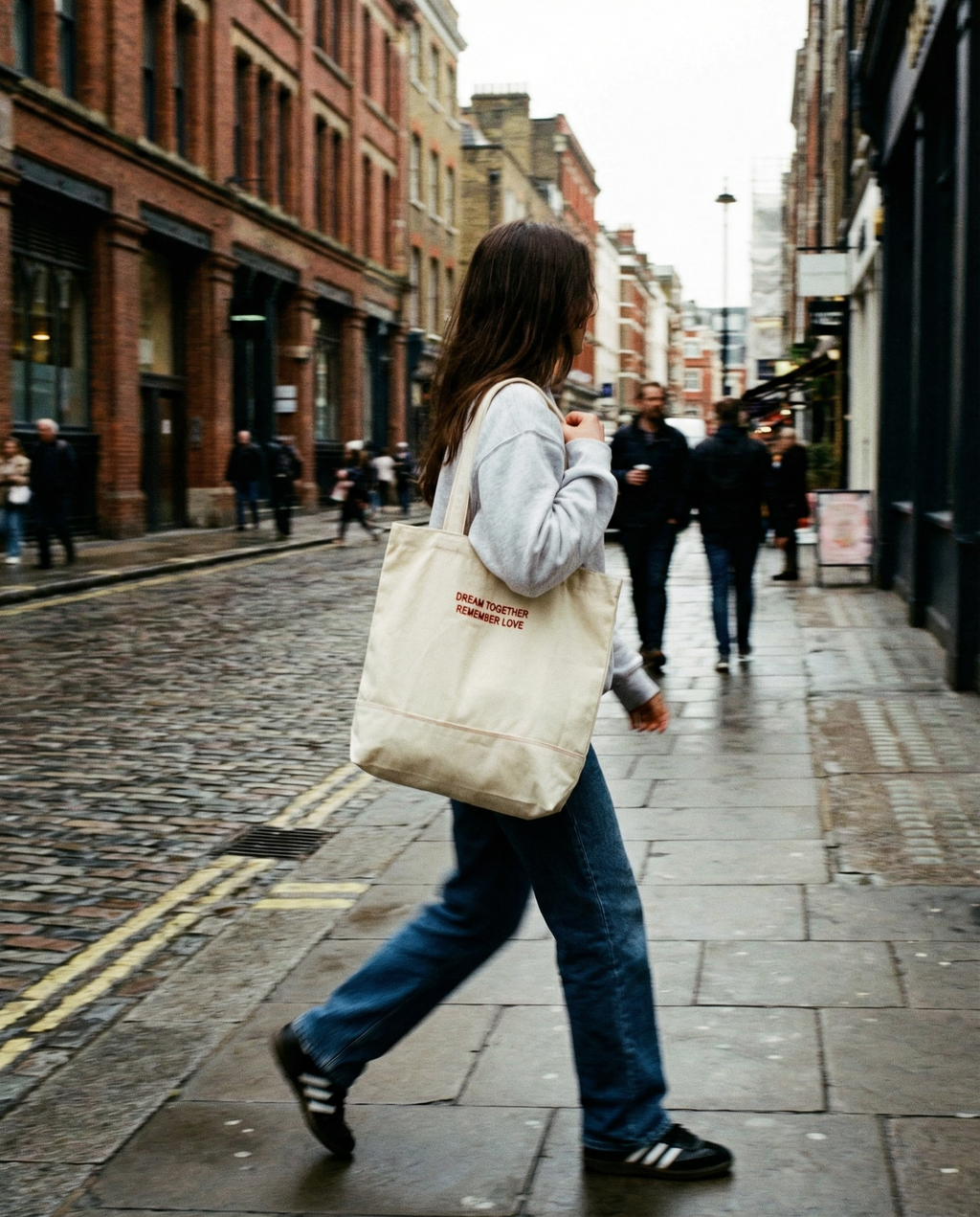 Person walking down a city street holding a tote bag.