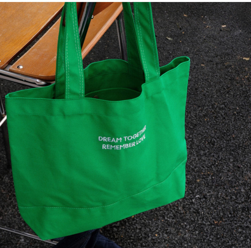 Green tote bag with text on a dark surface