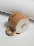 Cozy brown handmade mug with text.